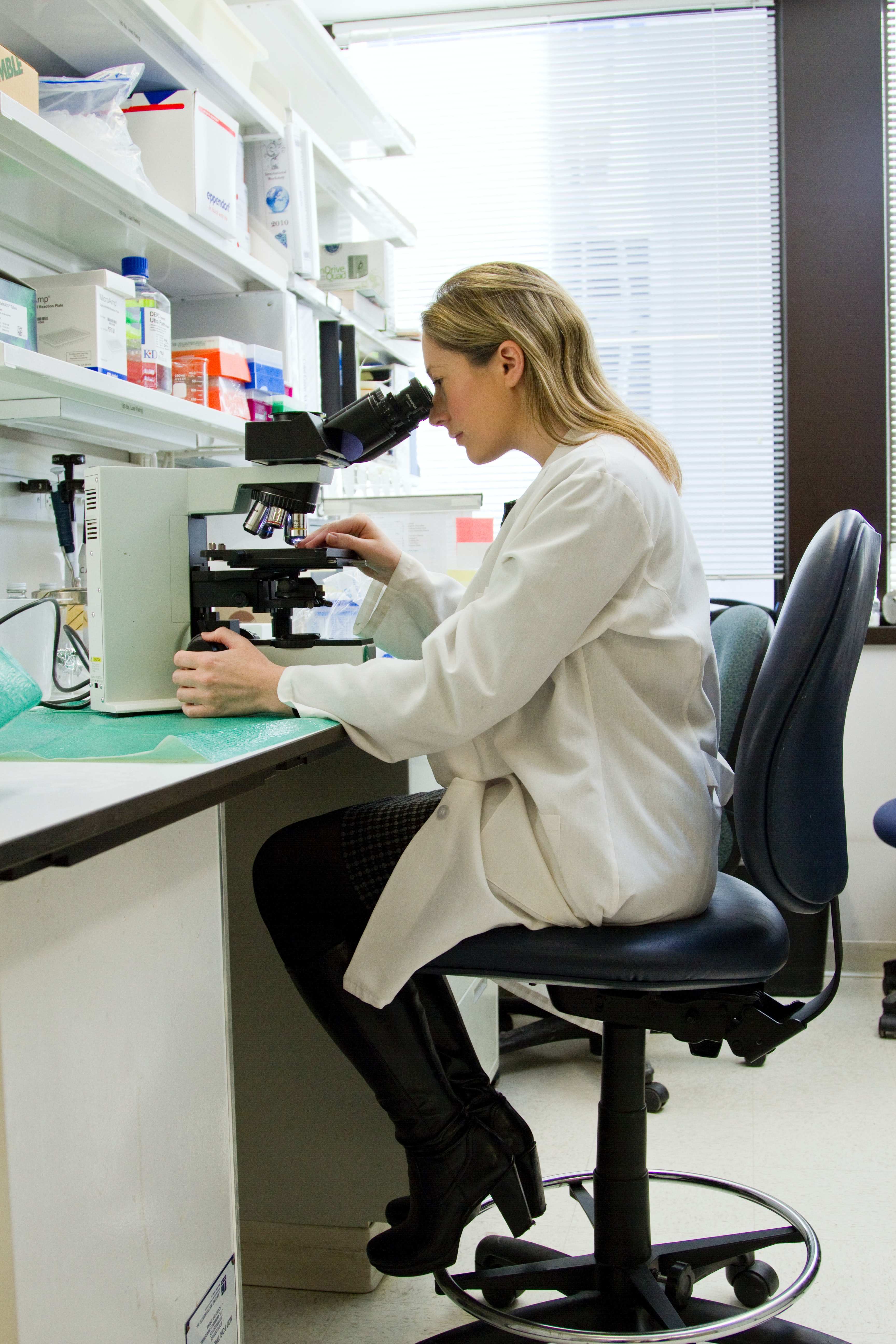 Woman with Microscope Woman in lab coat looking into microscope.